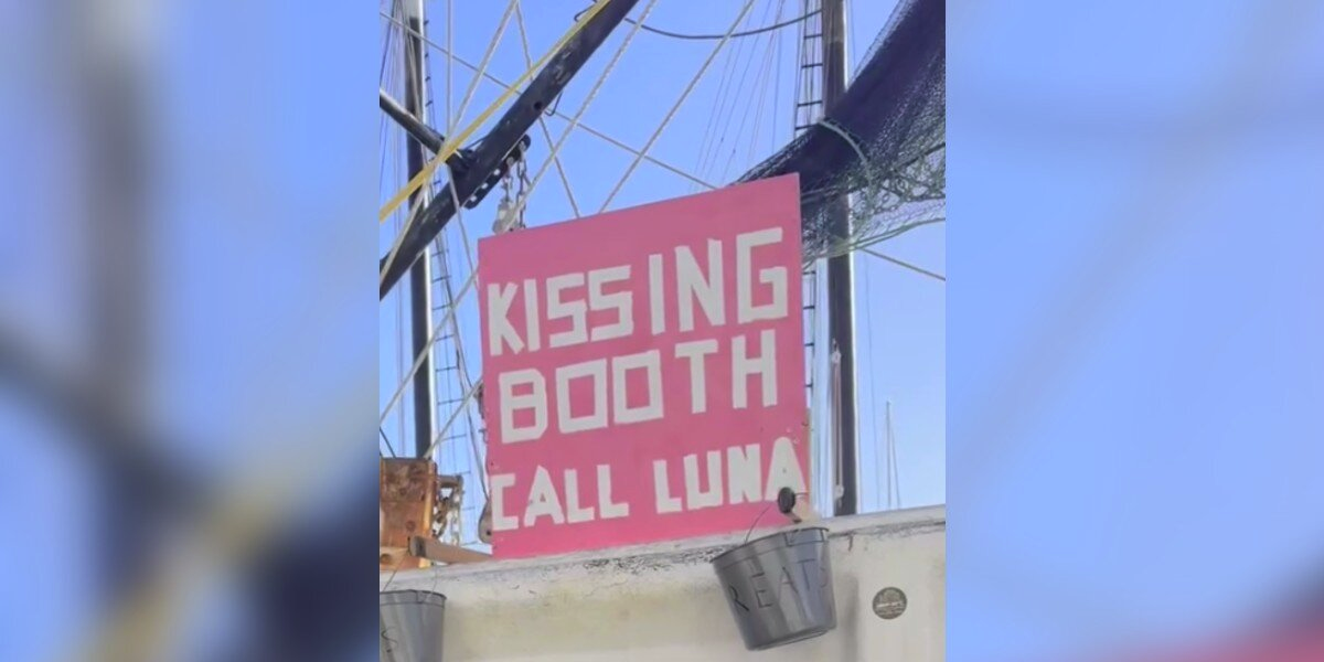 Tourists Spot 'Kissing Booth' Sign On Docked Boat — Then A Sweet Dog Pops Into View